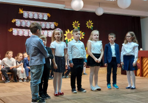 Kilkoro uczniów występuje na scenie recytując wiersze.