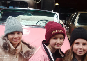 2.Trzy uśmiechnięte uczennice pozują w Muzeum Motoryzacji przed autem Marilyn Monroe.
