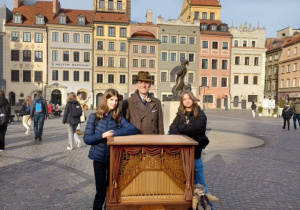 Dwie uśmiechnięte uczennice klasy 8a stojące obok pana kataryniarza.