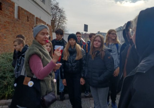 Pani przewodnik stojąca przy pomniku Małego Powstańca opowiada uczniom o jego tragicznej historii.