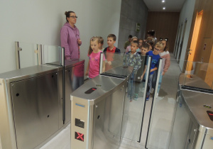 Dzieci ustawione jeden za drugim przechodzą przez elektroniczne bramki.