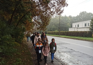 Ta sama ulica, ta sama grupa, ale w oddali widać następne osoby – dorosłych i dzieci.