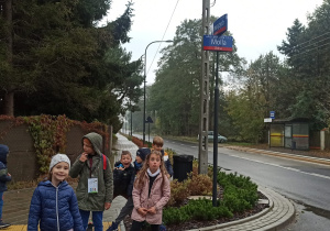 Skrzyżowanie ulic: Podchorążych i prof. Jana Molla. Pod krzyżującymi się tabliczkami z nazwami stoi siedmioro dzieci, kilkoro z nich patrzy w obiektyw. Dziewczynka na samym przedzie uśmiecha się, a jej koleżanka po prawej robi śmieszną minę do aparatu. Z tyłu – rozbawiony chłopiec.