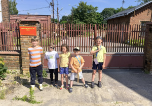 Na pierwszym planie pięcioro dzieci w letnich strojach, a za nimi ośmioro dorosłych. Wszyscy są roześmiani i wyglądają bardzo radośnie.