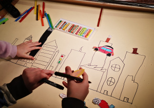 Dzieci wykonujące rysunek na kartonie.