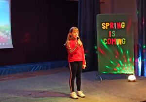 Dziewczynka recytująca wiersz na scenie.
