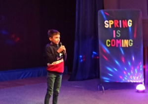 Chłopiec recytujący wiersz na scenie.