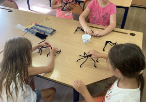 Uczennice tworzące pająki z drucików kreatywnych na warsztatach artystycznych.