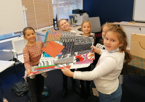 Grupka uśmiechniętych dziewczynek prezentuje skończoną pracę plastyczną.