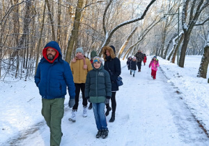 Grupa osób idzie alejką parku.