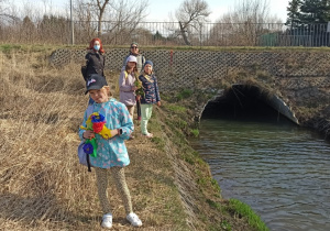 Cztery dziewczynki i jedna kobieta pozują do zdjęcia na tym samym brzegu rzeki.