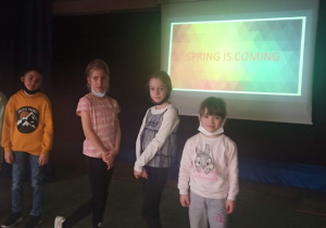 Cztery dziewczynki i jeden chłopiec stoją na scenie, w tle napis: spring is coming.
