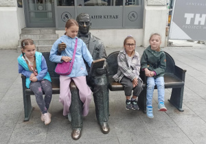 Cztery dziewczynki przy figurze Stefana Jaracza, trzy siedzą na krzesłach teatralnych, jedna na kolanie Jaracza.