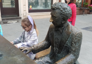 Dwie dziewczynki przy Fortepianie Rubinsteina, jedna z dziewczynek siedzi obok pianisty.