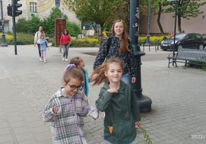 Trzy panie i cztery dziewczynki przechodzą przez ulicę w centrum miasta.