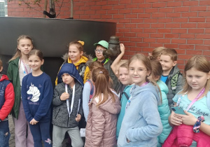 Grupa dzieci otaczająca figurę Ferdynanda Wspaniałego przed wejściem do Galerii Łódzkiej.
