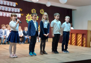 Kilkoro dzieci występuje na scenie grając scenkę o uczniu, który zmienił swoje zachowanie.