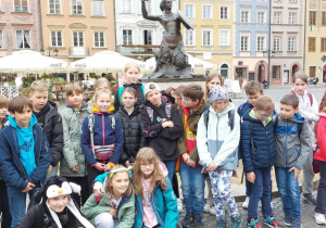 Rynek Starego Miasta w Warszawie. Uczniowie klasy 4a stoją pod pomnikiem Syrenki, w tle zabytkowe kamienice.