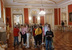 Zamek Królewski w Warszawie - Sala Rady. Uczniowie oglądają obrazy i rzeźby, dziewczynka robi zdjęcia.