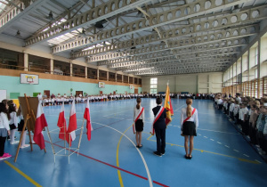 Zdjęcie przedstawiające uczniów i pracowników szkoły znajdujących się w sali gimnastycznej.