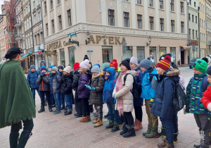 Dzieci słuchające przewodnika na rynku Toruńskim.