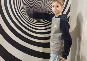 Muzeum Iluzji w Warszawie. Uczeń pokazuje działanie iluzji.