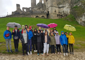 Uczniowie pod kolorowymi parasolami, w tle ruiny Zamku Ogrodzieniec.