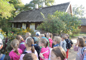 Dzieci stoją przed wiejską chatą.