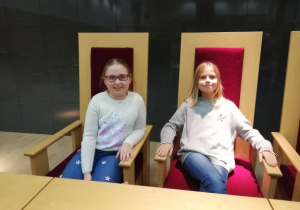 Dziewczynki siedzące w sali sądowej.