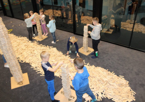 Dzieci w grupach budują wieże z klocków Linden.
