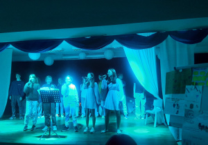 Dziewczynki stoją na scenie i śpiewają piosenkę.