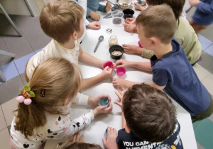 Grupa kolonijna uczestniczy w warsztatach mydlarskich, robiąc własne mydło.
