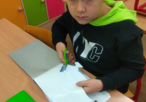Chłopiec wycinający z kolorowego papieru.