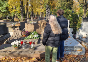 Uczniowie (chłopiec i dziewczynka) stoją w zadumie przy grobie prof. Jana Molla.