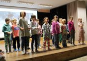 Sala widowiskowa. Na scenie stoi grupa dzieci w trzech rzędach .Śpiewają piosenkę. Dziewczynka stojąca w pierwszym rzędzie z prawej strony trzyma mikrofon.
