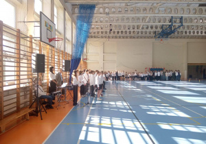 02 - widok na część sali gimnastycznej, gdzie uczniowie i nauczyciele odpowiedzialni za uroczystość oczekują na oficjalne rozpoczęcie uroczystości.