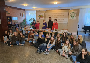 Grupa uczniów wraz z nauczycielem znajdują się w holu głównym szkoły.