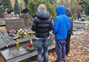 Delegacja trojga uczniów przy pomniku patrona