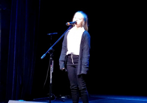 Dziewczynka śpiewająca piosenkę na scenie.