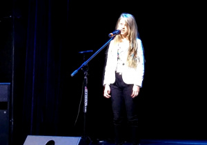 Dziewczynka śpiewająca piosenkę na scenie.