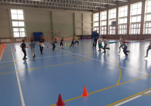 Uczniowie biegający w sali gimnastycznej.